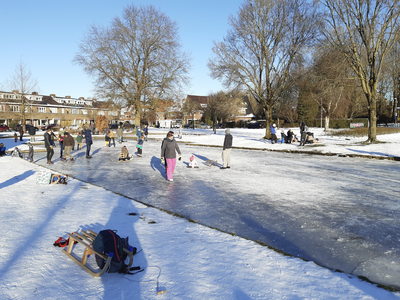 901390 Afbeelding van schaatsende mensen en spelende kinderen op het ijs bij het Willem de Zwijgerplantsoen te Utrecht, ...